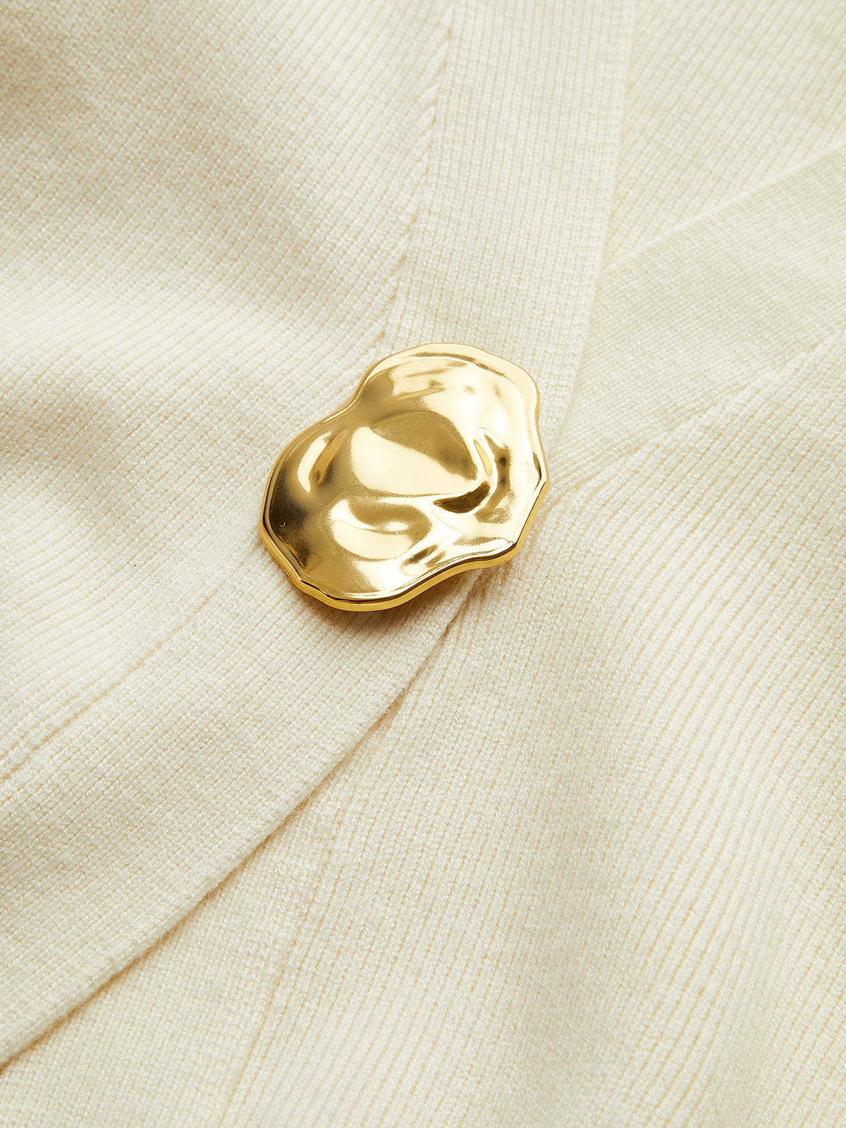 Zacht vest met klassieke gouden knoop